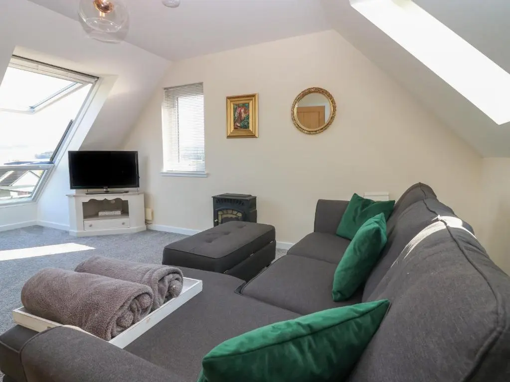 a living room with a couch and a tv at Berg Cottage in Ballindalloch
