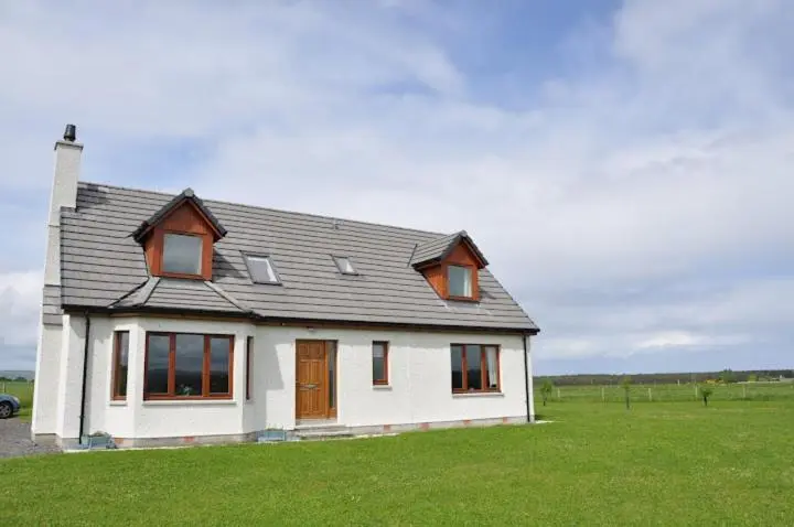 a white house with a gray roof on a green field at Ard Garraidh in Ardersier