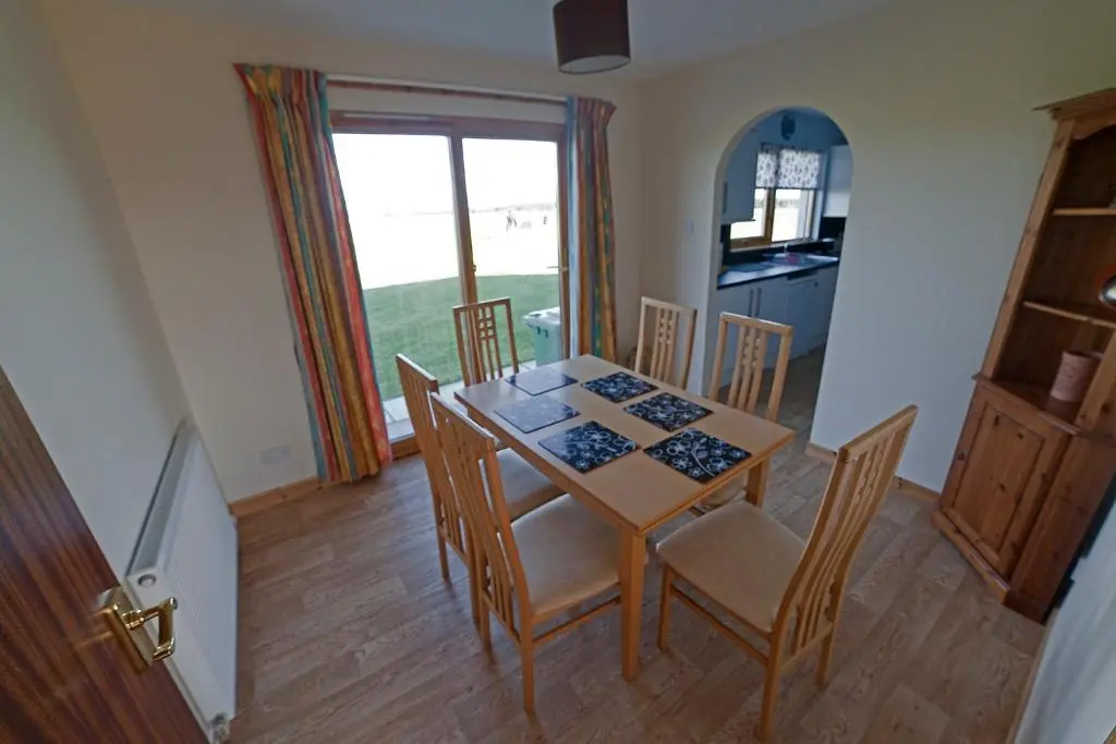 a dining room with a table and chairs and a window at Ard Garraidh in Ardersier