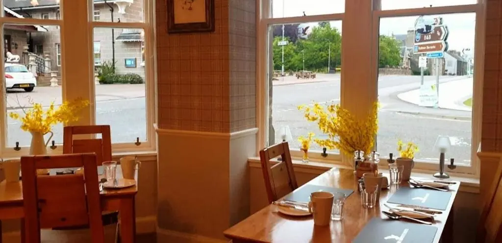 a dining room with tables and chairs and a window at The Osprey Hotel in Kingussie