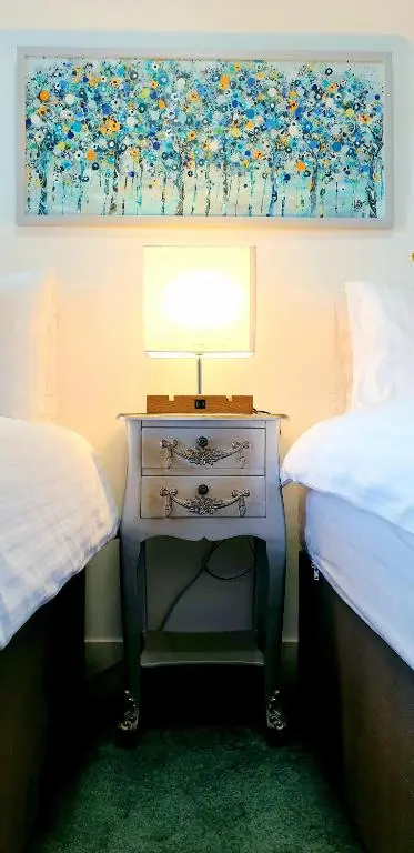 a table with a lamp on it next to two beds at The Osprey Hotel in Kingussie
