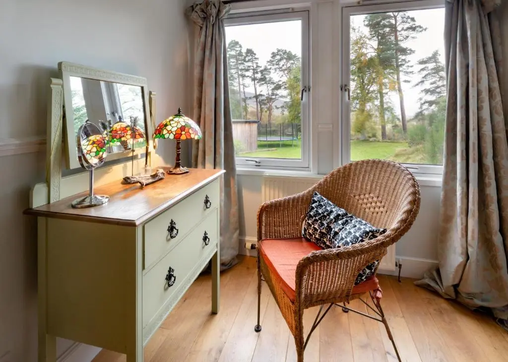 a bedroom with a dresser and a chair and a mirror at Wee Wilds in Newtonmore