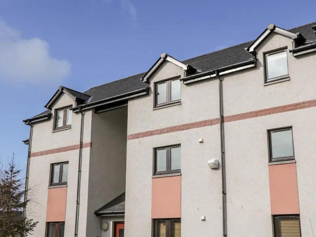 a large white building with a black roof at Riverview Apartment in Inverness