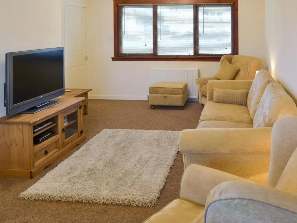 a living room with couches and a flat screen tv at Cluaran Cottage in Tain