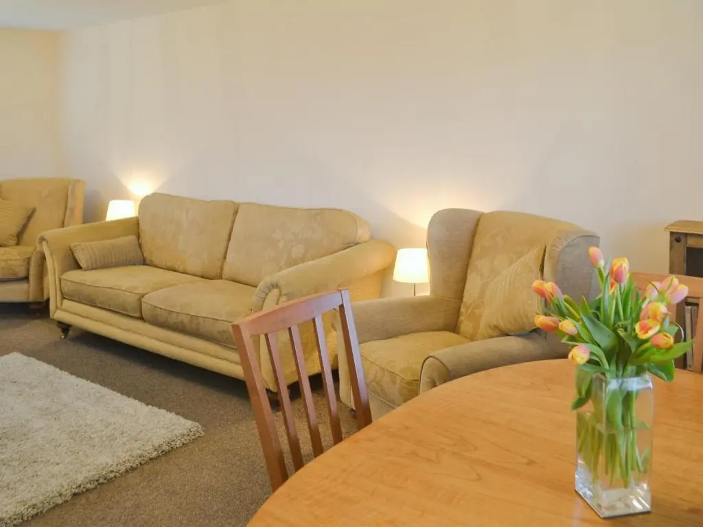 a living room with a couch and a table with flowers at Cluaran Cottage in Tain