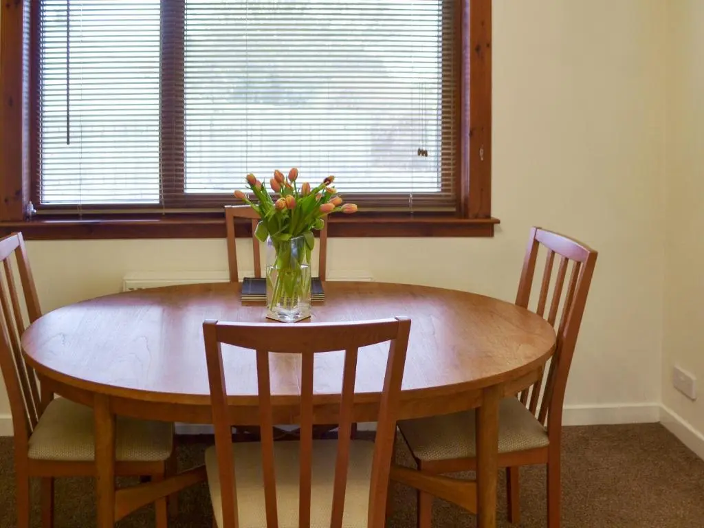 a dining room table with a vase of flowers on it at Cluaran Cottage in Tain