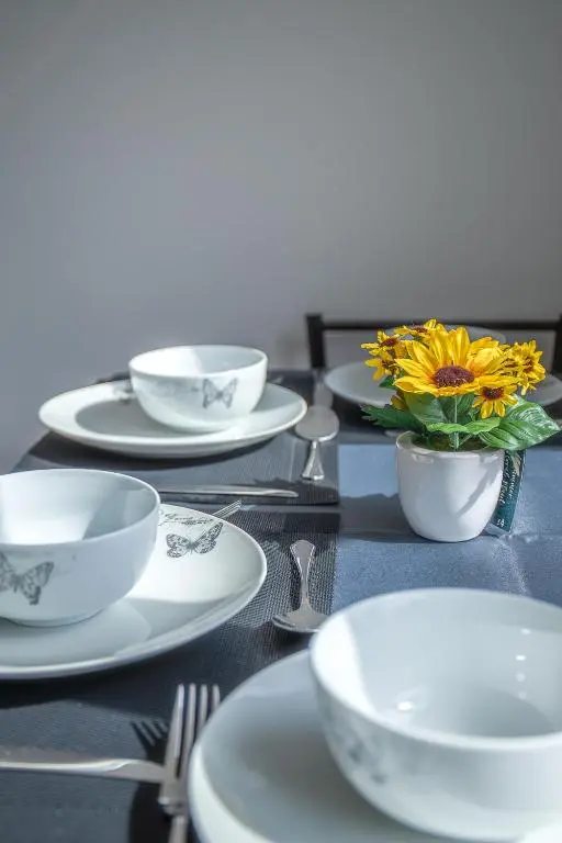 a table with plates and bowls and a vase of flowers at Millburn Apartment in Inverness
