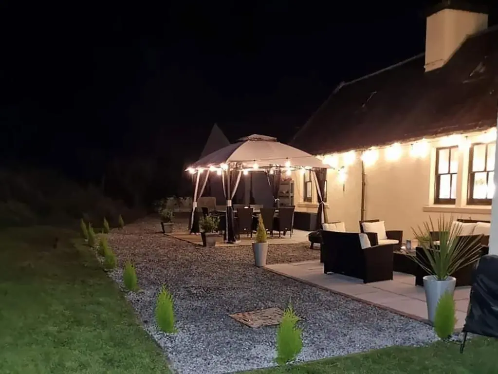 a patio at night with an umbrella and chairs at Antfield House in Lochend