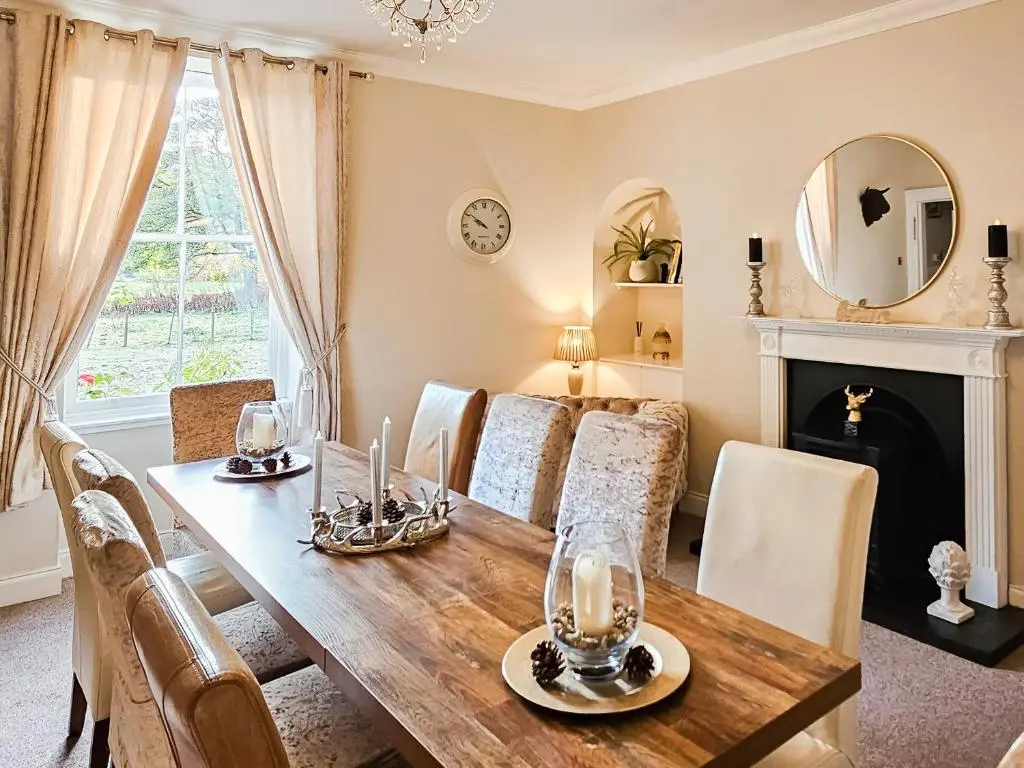a dining room with a table and chairs and a fireplace at Antfield House in Lochend