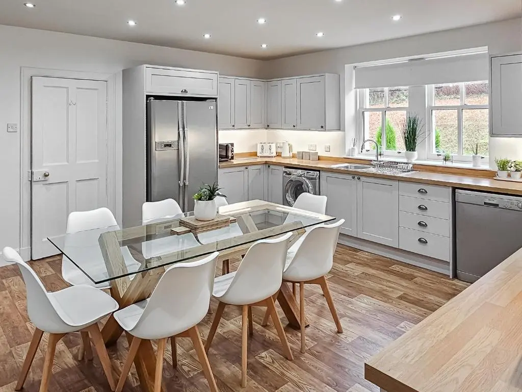 a kitchen with a glass table and white chairs at Antfield House in Lochend
