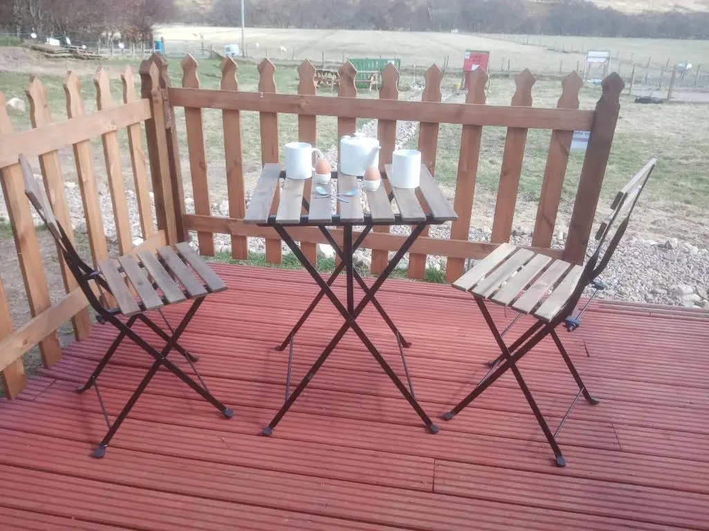 two chairs and a table with cups and mugs on it at Wee Hoose Glaping Pod 2 in Skail