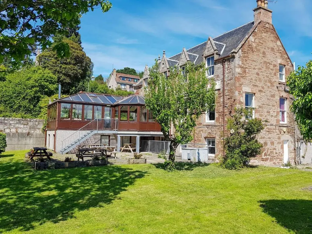 a large brick building with a table in a yard at The Pine Martin - Uk31005 in Avoch
