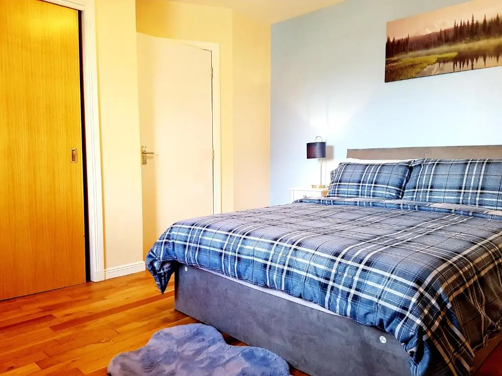 a bedroom with a bed with a blue plaid blanket at Inverness City 2 bedroom free parking in Inverness