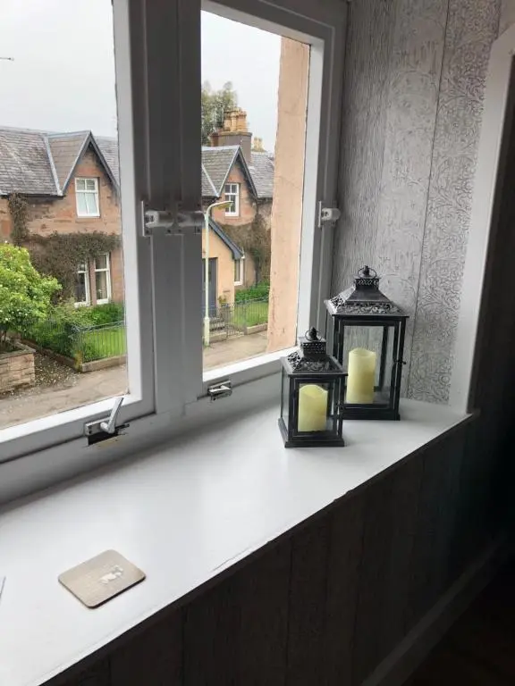 two candles on a window sill with a view at Thistle Apartment, Inverness in Inverness