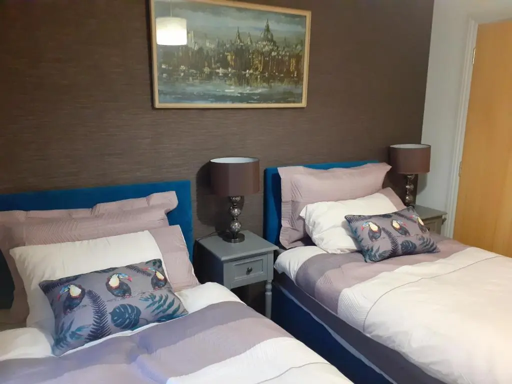 a bedroom with two beds and a painting on the wall at Bishops Park Apartment in Inverness
