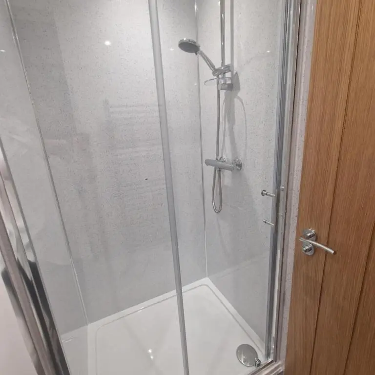a shower in a bathroom with a glass door at Pleasant Point Holiday Cottages in Rosemarkie