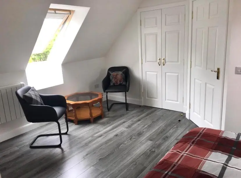 a attic room with two chairs and a window at Kilberry Guest House in Beauly