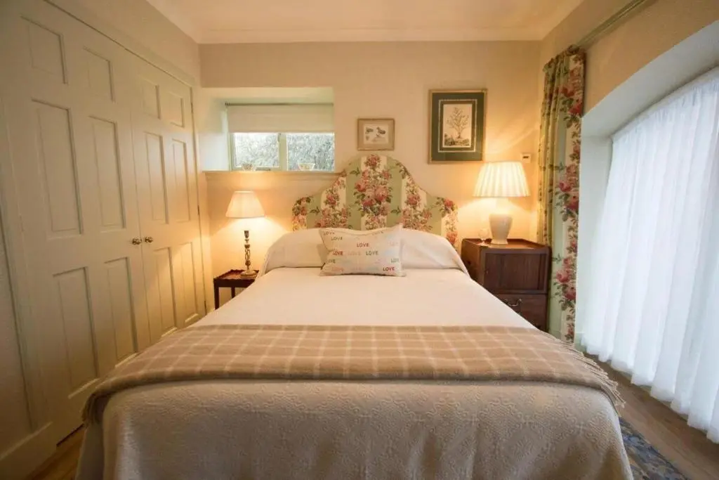 a bedroom with a bed and two lamps and a window at Balnagown Estates Peat Cottage in Kildary