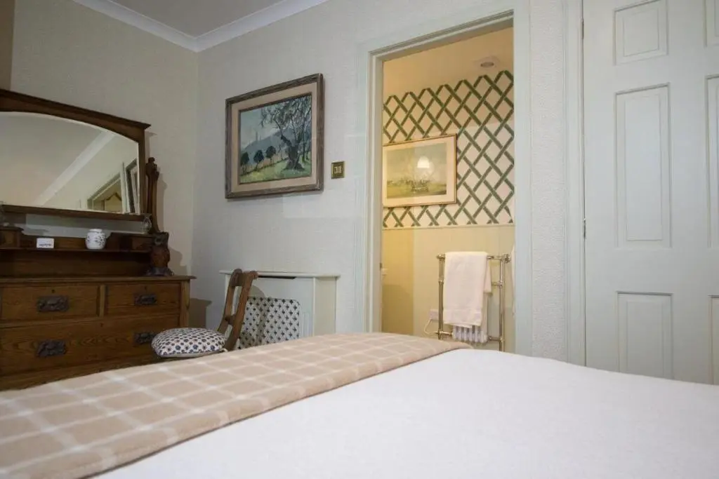 a bedroom with a bed and a dresser and a mirror at Balnagown Estates Peat Cottage in Kildary