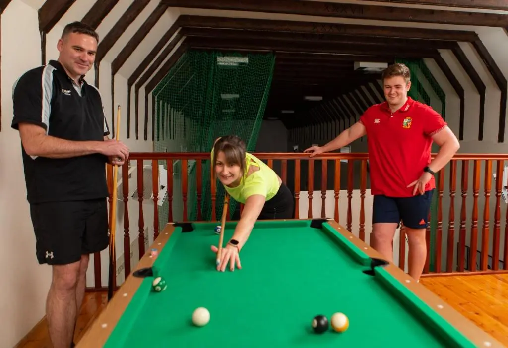 two men and a girl playing a game of pool at Balnagown Estates Swiss Cottage in Barbaraville