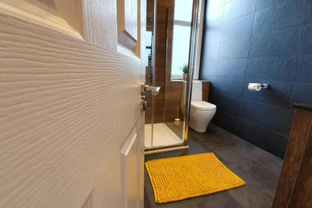 a bathroom with a toilet and a door with a yellow rug at Smart & Stylish Holiday Apartment in the city centre in Inverness