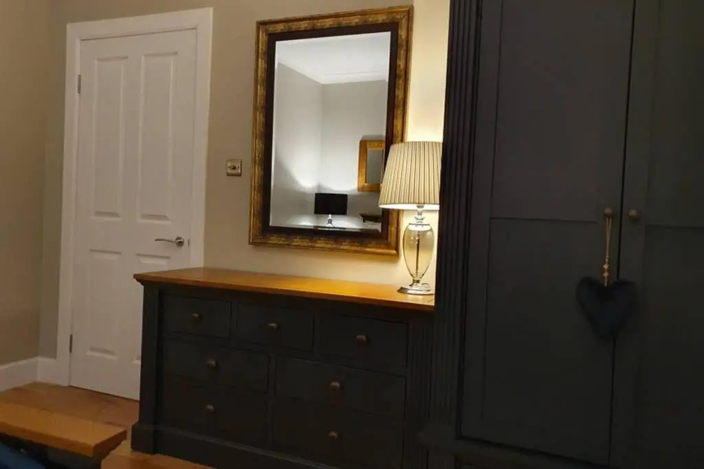 a dresser with a mirror and a lamp on it at Smart & Stylish Holiday Apartment in the city centre in Inverness