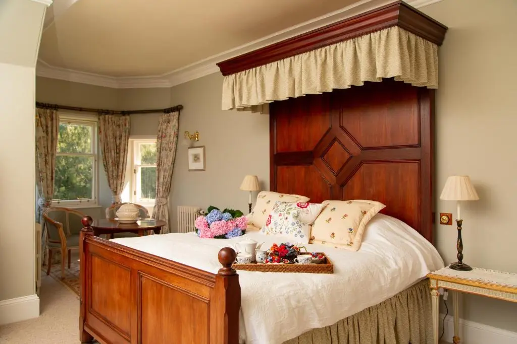 a bedroom with a large bed with a wooden headboard at Inveroykel Lodge at Rosehall in Rosehall