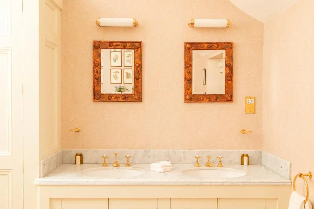 a bathroom with two sinks and two mirrors at Inveroykel Lodge at Rosehall in Rosehall
