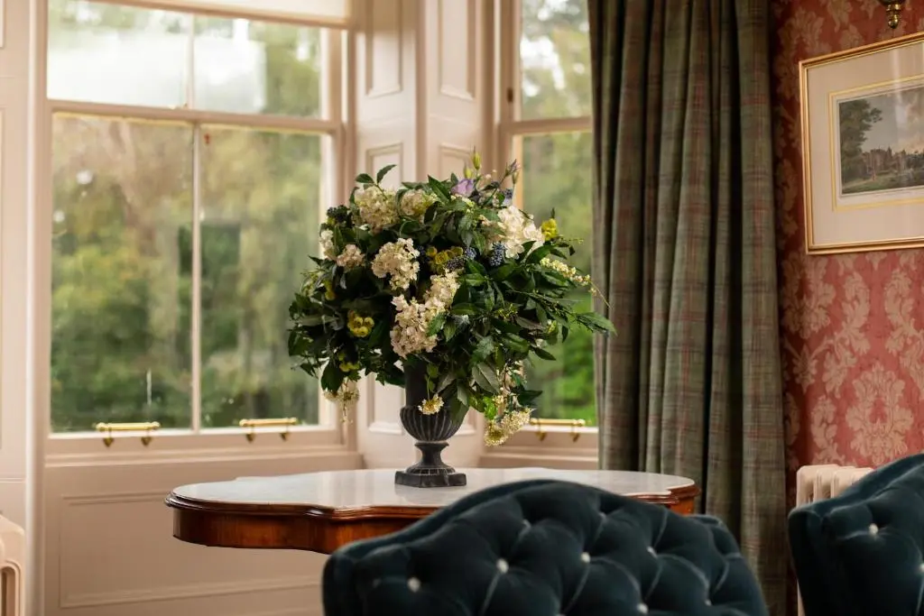 a vase of flowers on a table in front of a window at Inveroykel Lodge at Rosehall in Rosehall