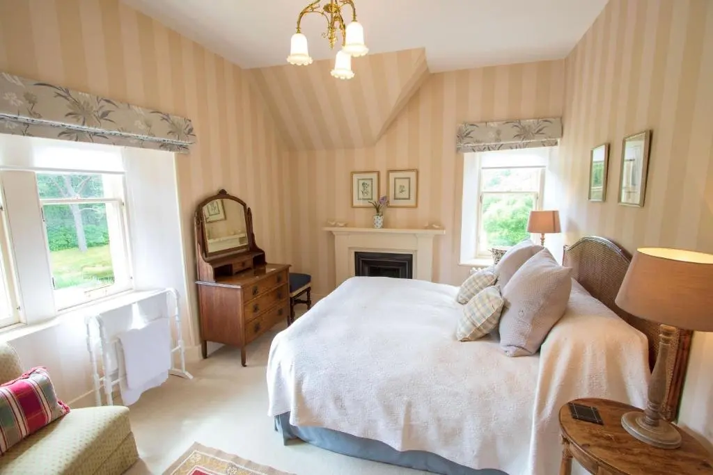 a bedroom with a white bed and a fireplace at Inveroykel Lodge at Rosehall in Rosehall
