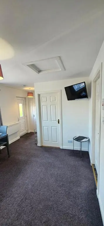 a room with a door and a tv on the wall at Arisaig Flat in Inverness