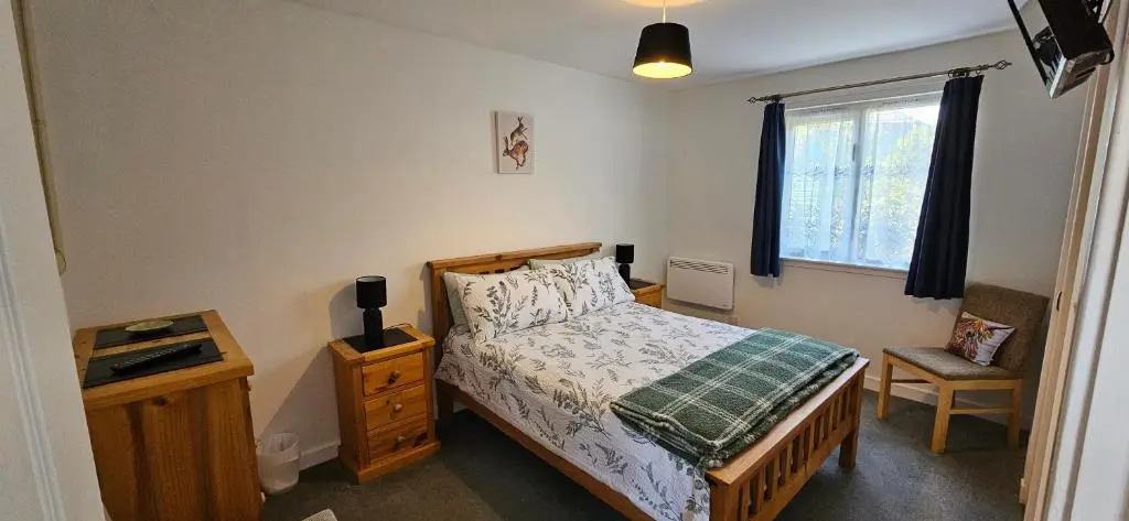 a small bedroom with a bed and a window at Arisaig Flat in Inverness