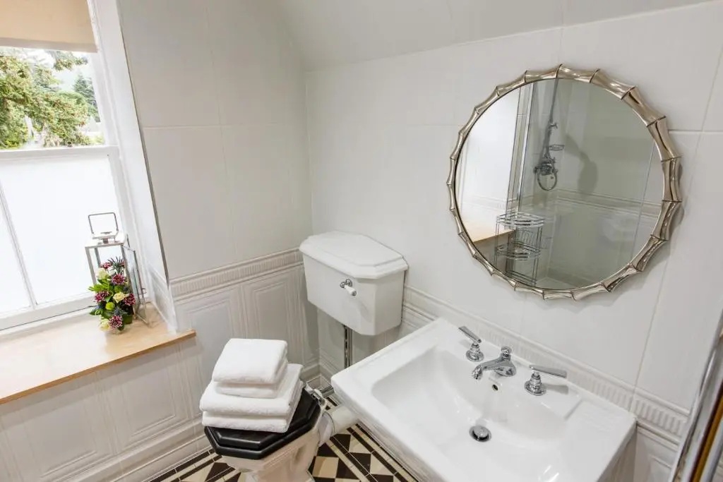 a white bathroom with a sink and a mirror at St Andrews House in Ballater