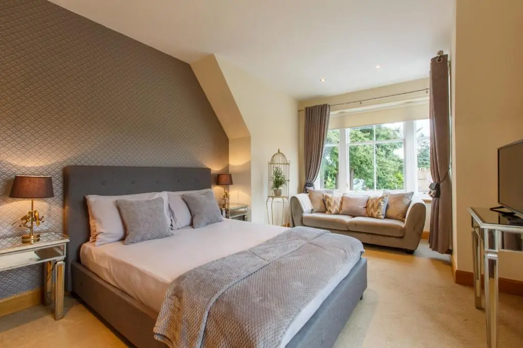 a bedroom with a bed and a couch and a television at St Andrews House in Ballater
