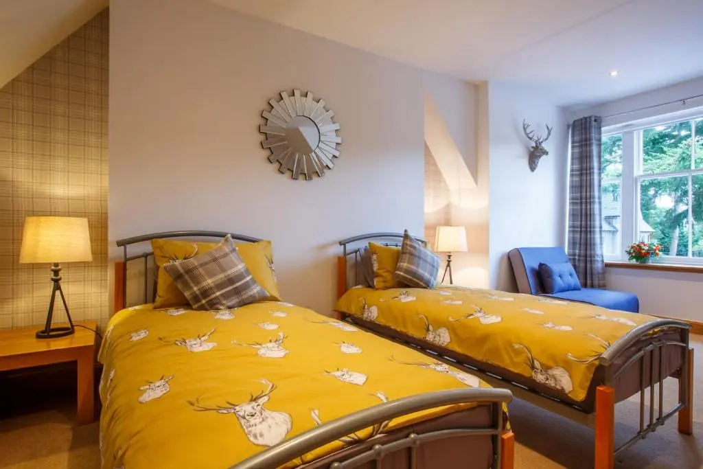 a bedroom with two beds and a mirror on the wall at St Andrews House in Ballater