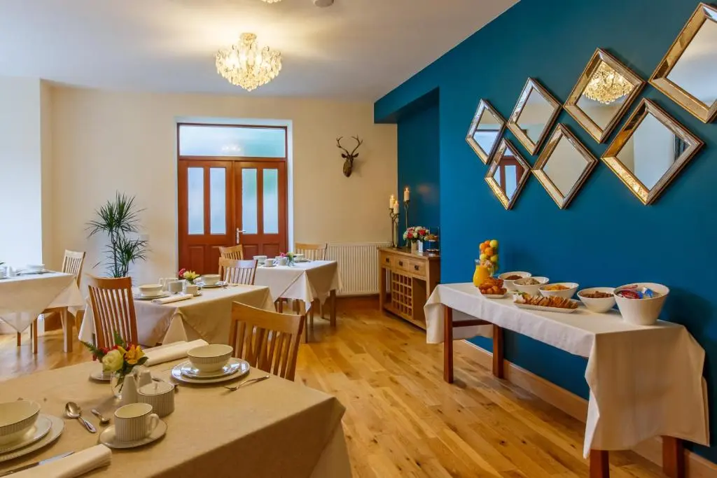 a dining room with tables and a blue wall at St Andrews House in Ballater