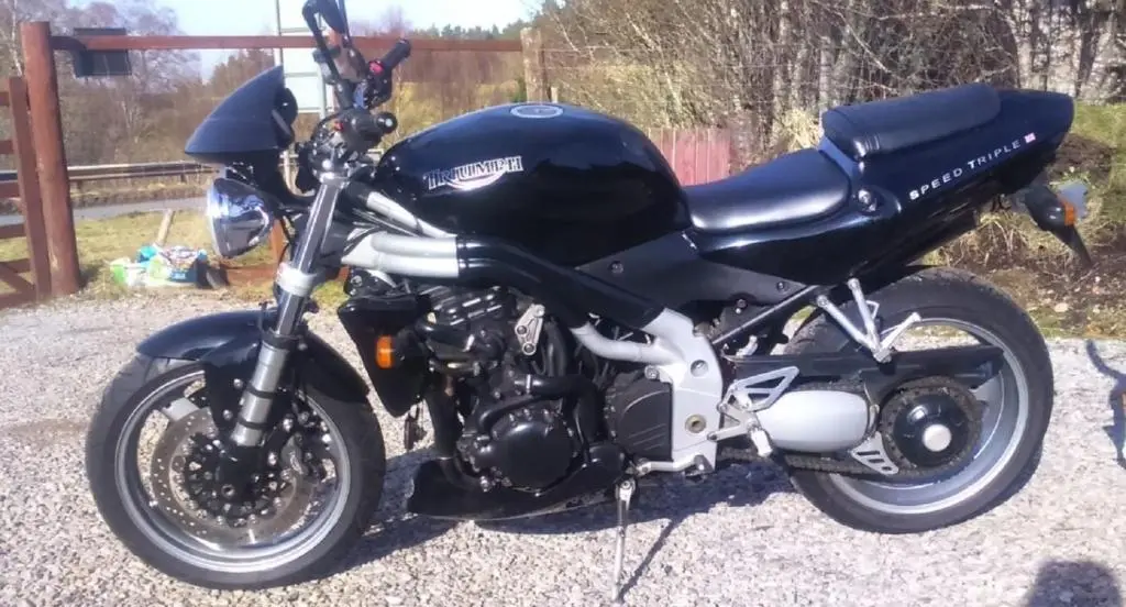a black motorcycle parked on a gravel road at Jakels Rest in Lairg