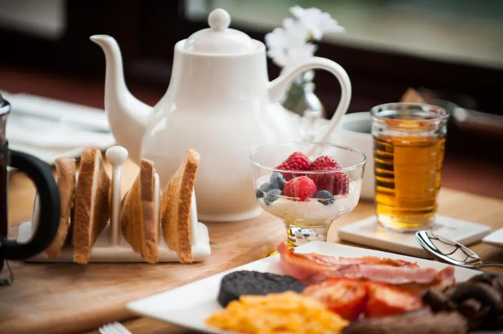 a table with a tea kettle and a plate of food at Kilmore Farmhouse in Drumnadrochit