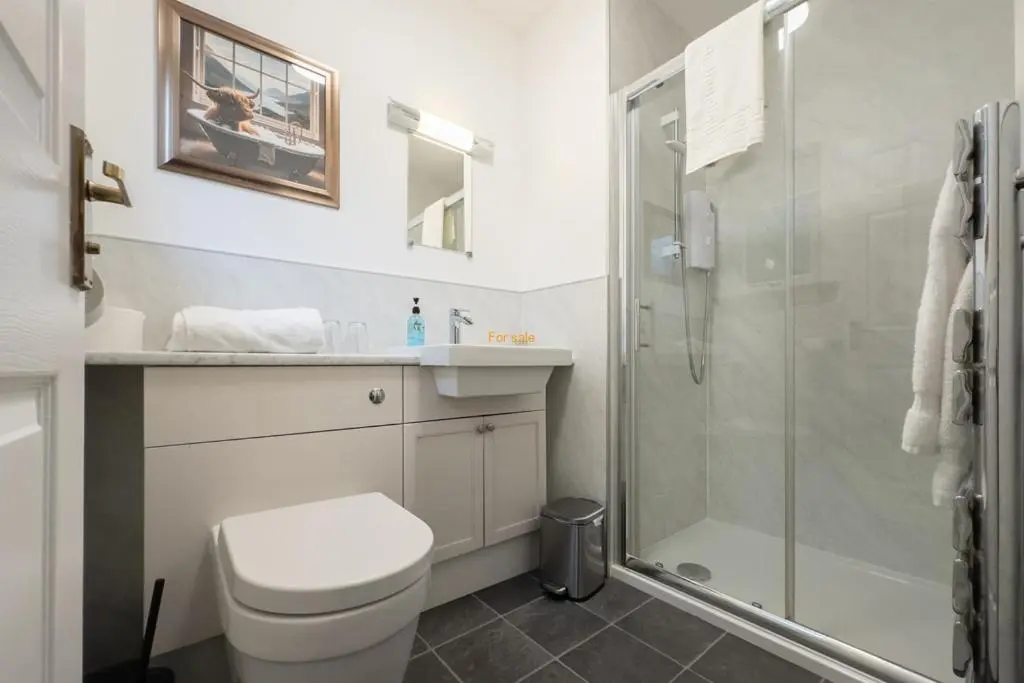 a white bathroom with a toilet and a shower at Kilmore Farmhouse in Drumnadrochit