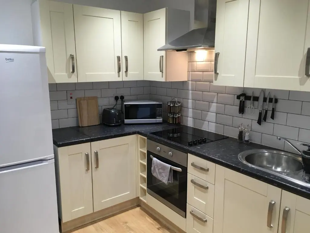 a kitchen with white cabinets and a sink and a microwave at Blarmore Apartment Inverness in Inverness