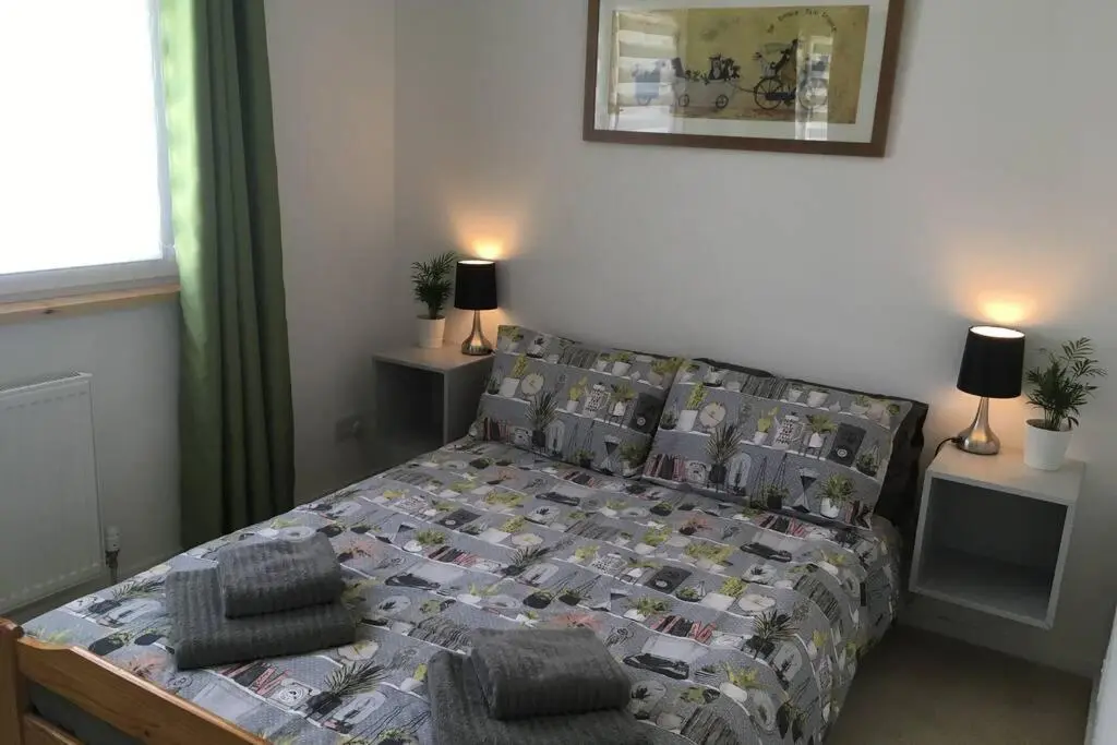 a bedroom with a bed with a comforter and pillows at Blarmore Apartment Inverness in Inverness
