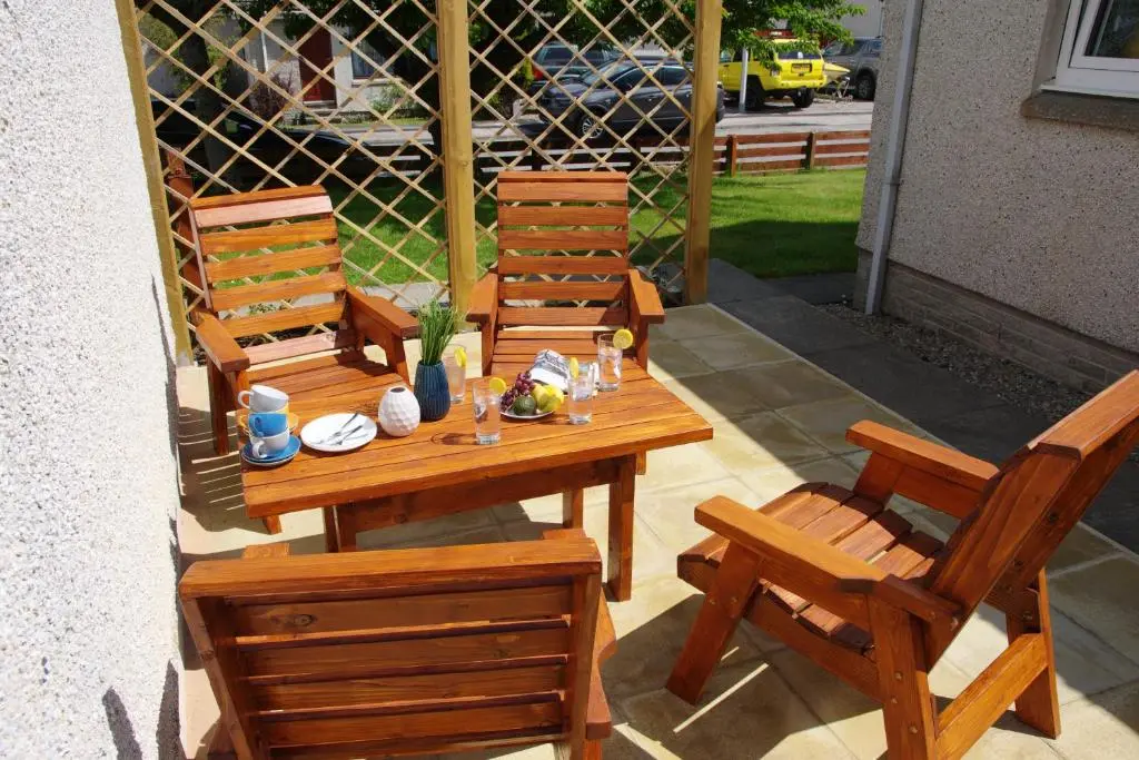 three wooden chairs and a wooden table and chairs at Blarmore Apartment Inverness in Inverness