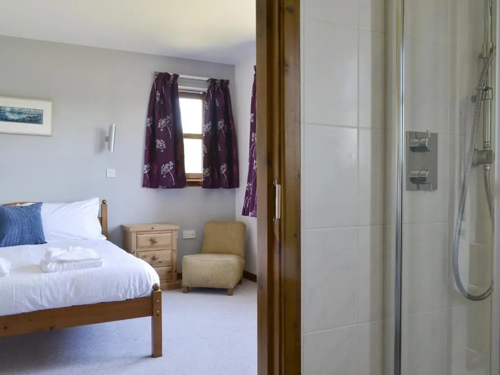 a bedroom with a bed and a glass shower at Battanropie Lodge in Carrbridge