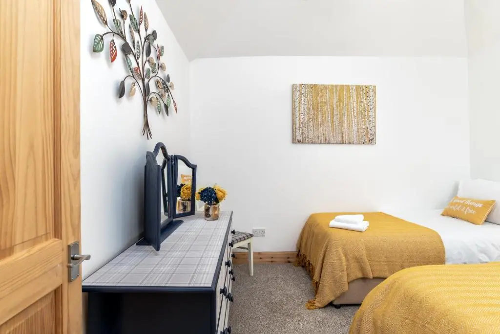 a bedroom with two beds and a tv on a table at Dormie Cottage, lovely bright and spacious bungalow with wood fire in Ballater