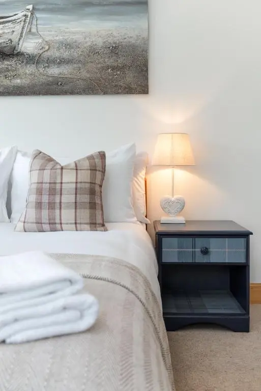 a bedroom with a bed and a table with a lamp at Dormie Cottage, lovely bright and spacious bungalow with wood fire in Ballater