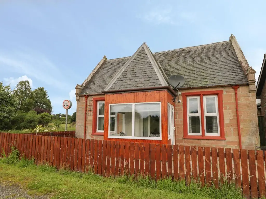 a small house with a fence in front of it at Blantyre Cottage in Muir of Ord