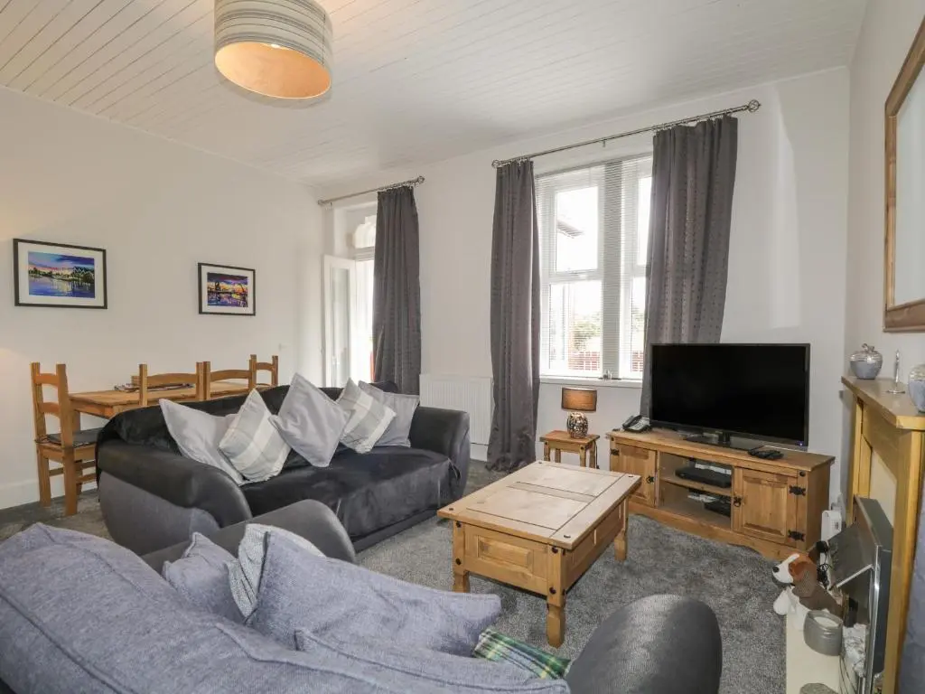 a living room with a couch and a tv at Blantyre Cottage in Muir of Ord