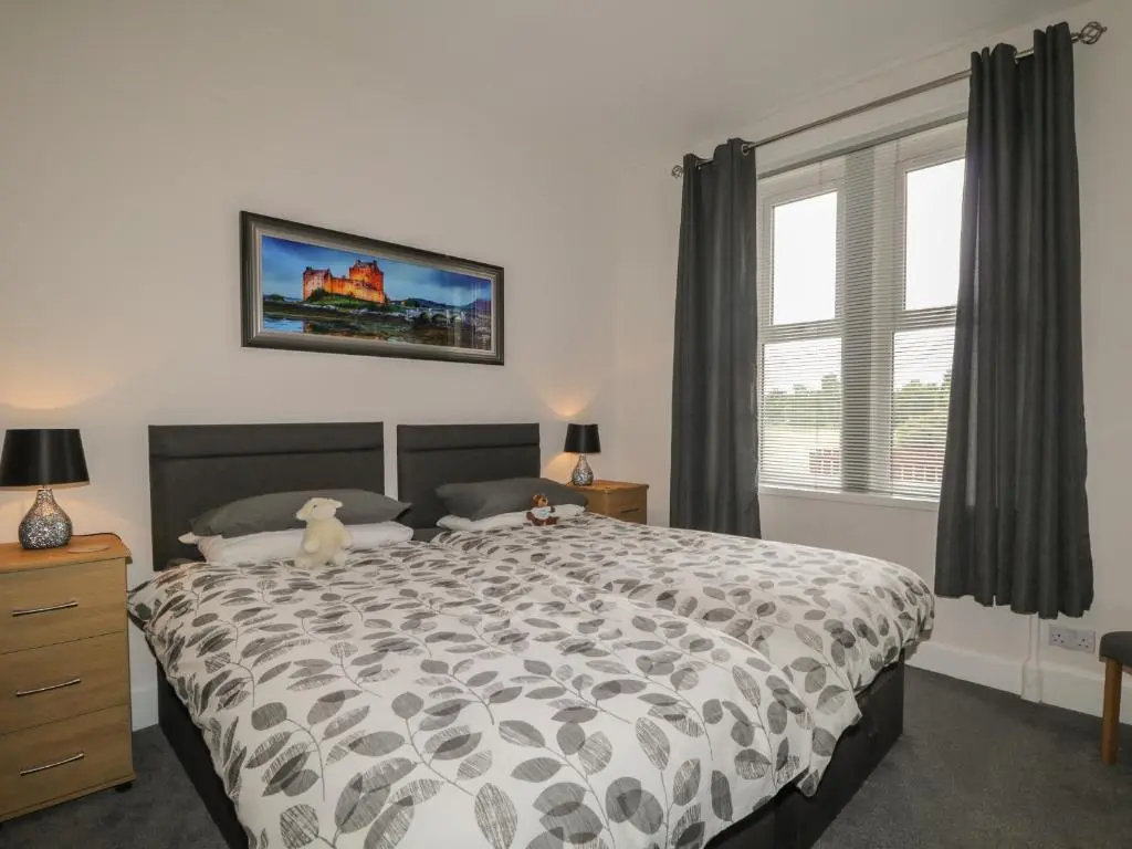 a bedroom with a large bed and a window at Blantyre Cottage in Muir of Ord