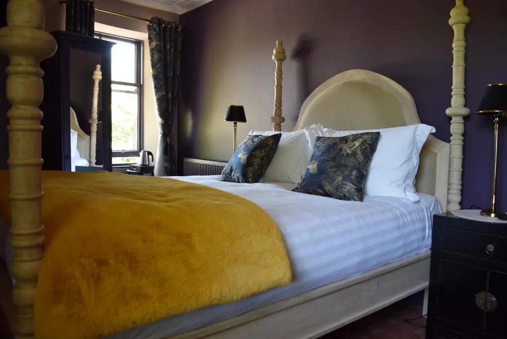 a bedroom with a large bed with a yellow blanket at The Mash Tun in Aberlour