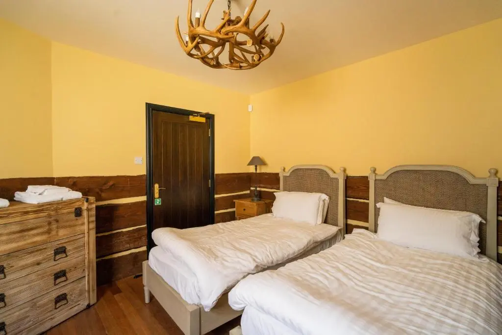 a bedroom with two beds and a chandelier at The Mash Tun in Aberlour